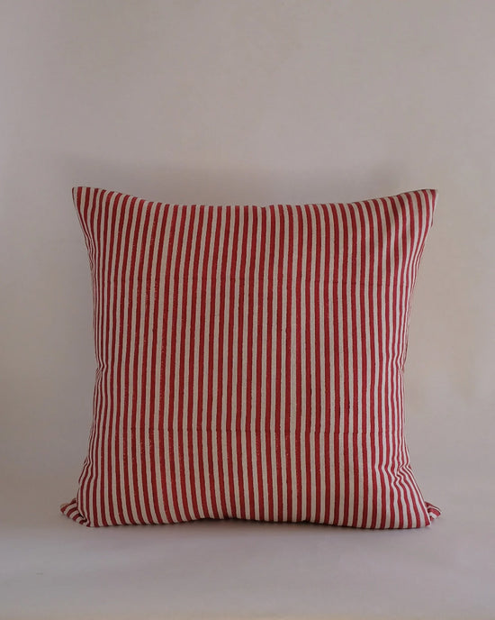 The Babita Linen Pillow - 22 x 22 in Red by Soil to Studio features red and white vertical stripes inspired by the Valley of Flowers, shown against a plain, light-colored background.