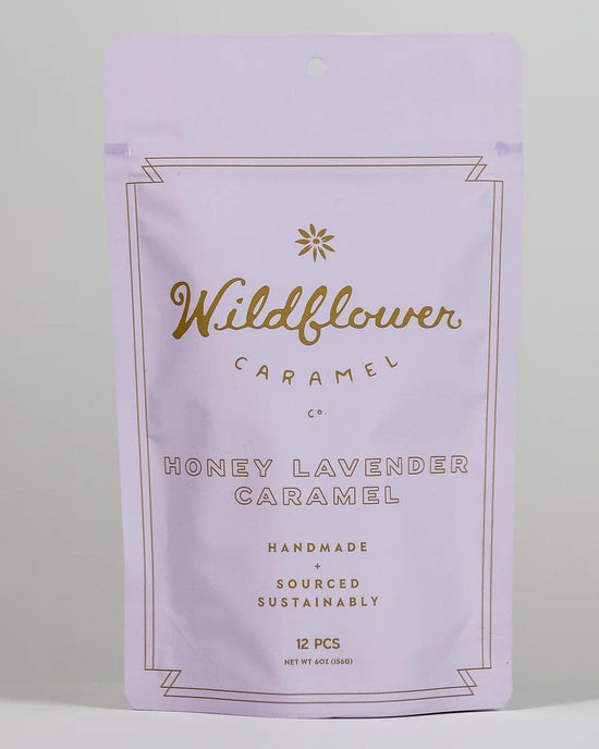 A lavender bag labeled Wildflower Caramel Co Honey Lavender Caramels contains 12 pieces of organic, handmade caramel with Texas honey. Gold, centered text highlights its sustainable sourcing.