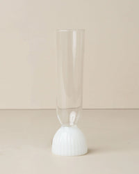 The Kairos Champagne Flute in Opaque White by Saarde features a sleek design, shown on a neutral surface with a beige background.