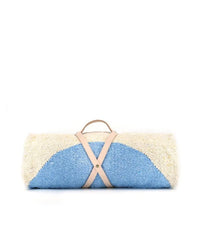 The Luna Lago - Blanket Roll by caminito is a rolled-up blue and off-white outdoor blanket with a light tan handmade leather strap and handle, shown against a plain white background.