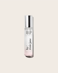 A clear glass bottle of Rosie Jane’s Perfume Oil in Leila Lou, topped with a silver cap, stands upright against a light beige backdrop, embodying its fresh floral scent.