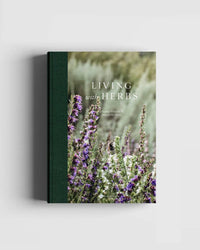 Living with Herbs" by Cozy Publishing is a hardcover book featuring blooming purple and white herbs on the cover, perfect for herb gardening enthusiasts, with a green spine and natural blurred background.