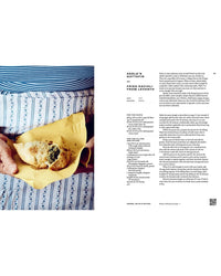 A person in a blue and white striped dress holds two fried ravioli on yellow parchment, next to a printed recipe—bringing authentic Italian flavors to life, just like the Pasta Grannies: Comfort Cookbook from Chronicle Books.