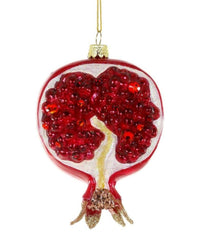 The Pomegranate Ornament by Cody Foster is a hand-crafted glass Christmas tree decoration featuring red seeds inside and a gold hanging loop at the top.