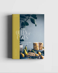 Queen of the Cakes – Gluten-Free Baking and Artistry by Cozy Publishing features gluten-free cake recipes and decorating tips, with a cover showing a cake, pears, and greenery against a blue-gray background.
