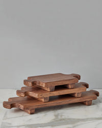 The etúHOME Normandy Wood Riser Footed Tray, Large, is displayed on a marble surface, stylishly elevating serveware and enhancing the look of any kitchen countertop board display.