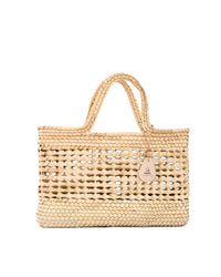 The caminito Canasta Chica Bag in Natural is a tan woven straw tote featuring double handles, an open-weave center design, and a small leather logo tag on one handle. The background is plain white.
