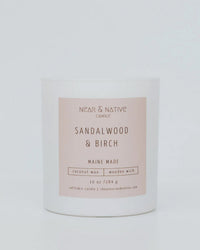 A 10 oz coconut wax wood wick candle by Near & Native in Sandalwood & Birch, Maine made with essential oils, in a simple glass jar with a beige label and refillable design.