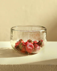 The Collective Pebbled Bowls - Set of 2 are hand-blown glass bowls, shown here with strawberries and stems on a light-colored surface against a neutral background.