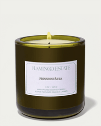 A green Flamingo Estate Prinsesstarta Candle featuring a single wick and a white label describes its almond marzipan scent. The candle is unlit and placed against a plain background.