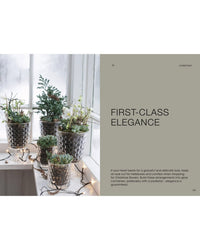 A windowsill adorned with potted succulents and white blooms in hammered silver pots, lit by string lights. On the right: “The Potted Garden - All Year Round” by Cozy Publishing—seasonal arrangements for a festive look.