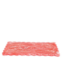 A single slice of wavy, pink deli meat is artfully displayed on a white background—perfect for serving atop the Casa Amarosa 14in Scallop Resin Rectangular Cheese Board in Pink.