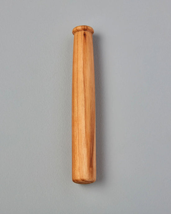 The Be Home US Teak Muddler stands vertically against a gray background—a stylish, compact tool ideal for any bar cart or for muddling cocktails.