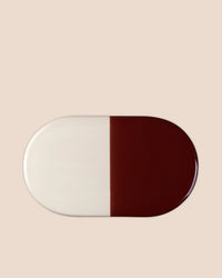 The Bergs Potter Nuna Glazed 13.4 x 7.9 Tray in Sandstone/Deep Burgundy features a food-safe, rectangular ceramic design with rounded edges and two equal color halves, crafted from durable glazed stoneware.