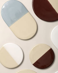 The Nuna Glazed 13.4 x 7.9 Tray by Bergs Potter features an oval stoneware design in Sandstone and Misty Blue, crafted from food-safe glazed ceramic and displayed on a neutral background.