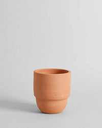 The Bloomist Big Cuff Planter | Medium is a plain, unglazed terra cotta piece with a rounded base and wide opening, ideal for indoor or outdoor use, shown against a neutral gray backdrop.