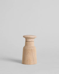 The Hammer Grinder | Oak by Bloomist—a compact, light oak spice mill with a rounded top and cylindrical base in classic Danish design—is set against a plain gray background.
