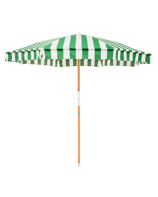 The Amalfi Umbrella - Crew Canyon Green Stripe by Business & Pleasure Co features a UV-resistant green and white striped canopy and a wooden pole, shown fully open against a white background.