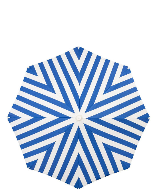 The Amalfi Umbrella - Crew Mediterranean Blue Stripe by Business & Pleasure Co features a top view of blue and white stripes radiating from the center, providing ample sun shade ideal for seaside relaxation.