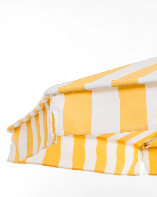 Close-up of the Amalfi Umbrella - Crew Mimosa Yellow Stripe by Business & Pleasure Co, featuring a yellow and white UV resistant canopy, set against a plain white background.