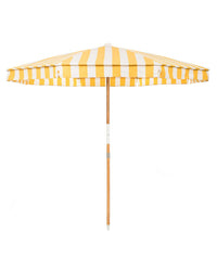 The Amalfi Umbrella - Crew Mimosa Yellow Stripe by Business & Pleasure Co features a yellow and white striped, UV-resistant canopy and a wooden pole, shown from the side against a plain white background.