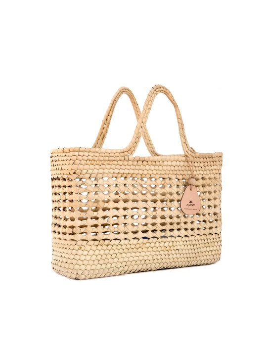 The caminito Canasta Chica Bag in Natural is a woven beige market tote with two handles and a small leather tag, shown against a white background.