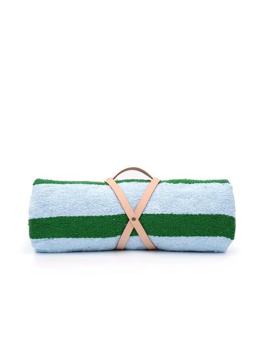 The caminito Marea Vuelta - Blanket Roll features light blue and green stripes, secured with a tan leather strap, shown against a white background—ideal for indoor or outdoor use.