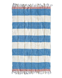The Suave Aire - Blanket Roll by caminito features horizontal blue and off-white stripes with pink bands at each end, fringed edges, and a slightly rough, handwoven texture reminiscent of natural fiber blankets.