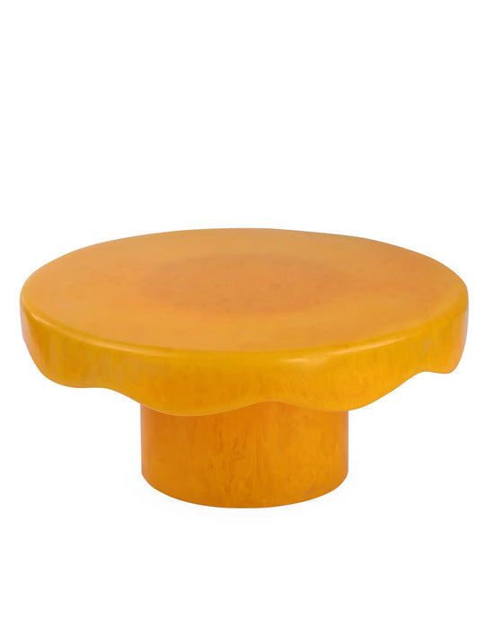The Scallop Resin Cake Stand in Mustard by Casa Amarosa features a round, yellow design with a wavy-edged top and cylindrical base, inspired by the playful style of a handmade cake stand.