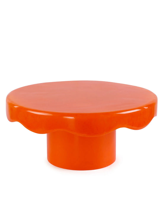 The Casa Amarosa Scallop Resin Cake Stand in Orange features a bright orange, round design with a wavy-edged tabletop and cylindrical base, displayed against a plain white background.