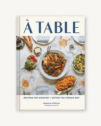 Cover of A Table by Chronicle Books, showing a French meal spread on a white table with plates, drinks, and dishes—perfect inspiration for French cooking at home.