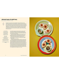 A recipe from Sicily, My Sweet by Chronicle Books appears on the left, while on the right are almond cookies and two cups of espresso on colorful plates set against a yellow background.