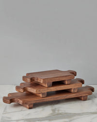 The etúHOME Normandy Wood Riser Footed Tray, Small, is displayed on a marble surface as elegant elevated serveware against a plain gray background.