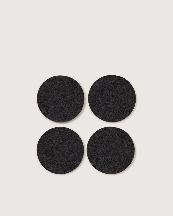 A set of four round Bierfilzl Merino Wool Felt Coasters in solid charcoal by graf lantz is arranged on a light background, offering a stylish and sustainable touch to any home decor.