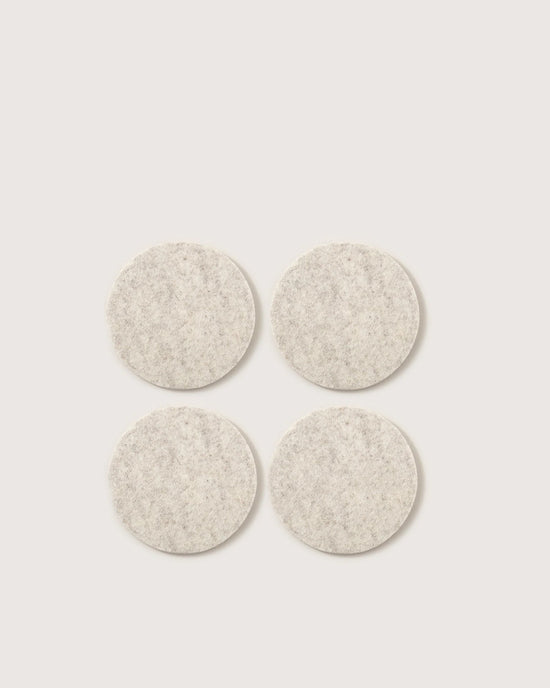 The graf lantz Bierfilzl Merino Wool Felt Round Coaster Solid in Heather White (4 Pack) offers an elegant, sustainable touch to your home decor with four light gray coasters arranged in a stylish square on any surface.