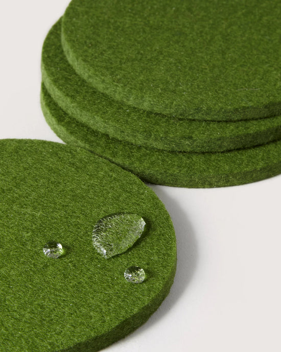 Four Loden Green Bierfilzl Merino Wool Felt Round Coasters by graf lantz are stacked, with one in front displaying three water droplets—showcasing the classic 4-pack style.