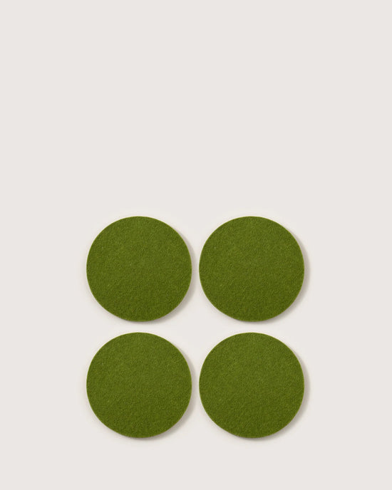 Four Bierfilzl Merino Wool Felt Round Coasters in Loden Green by graf lantz are arranged in a square on a plain, light background.