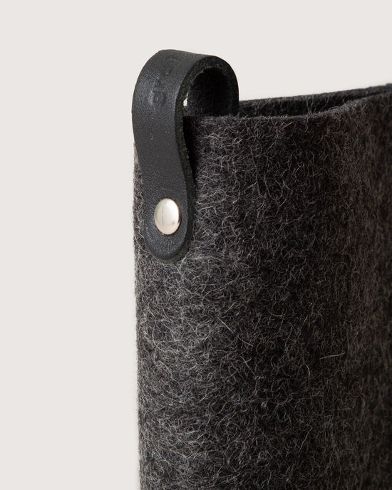 Close-up of the graf lantz Merino Wool Felt Anzen Eyeglass Sleeve in Charcoal, with a black leather loop and metal rivet, offering stylish protection for your eyewear against a plain background.