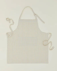 The Hawkins New York Essential Check Apron in Ivory/Flax features a white cotton design with thin brown grid lines, plus adjustable neck and waist ties for the perfect fit—a thoughtful kitchen gift for any cooking enthusiast.