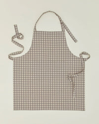 The Hawkins New York Essential Check Apron in Light Grey/Dark Grey features a chic check pattern, neck loop, and long waist ties—an elegant kitchen accessory, shown laid flat on a light background.