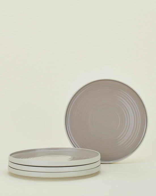 Four Essential Dinner Plates in Light Grey by Hawkins New York; three are stacked, one stands behind. The stoneware plates feature a subtle concentric circle pattern. Set of 4.