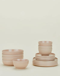 The Hawkins New York Essential Dinnerware in Blush, a 16-piece stoneware set, features stacked bowls and plates on a light background. Stylish and dishwasher safe.