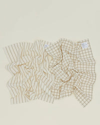 The Hawkins New York Essential Dish Towels in Flax/Ivory (Set of 2) are shown on a light surface; crafted from Oeko-Tex cotton, one towel features vertical stripes and the other a grid pattern.