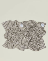 A set of two Hawkins New York Essential Dish Towels in Light Grey/Black—one striped, one checkered—lies side by side on a light surface.