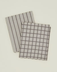 Set of 2 Essential Dish Towels by Hawkins New York in Light Grey/Black—one with vertical stripes and one checkered. Made from soft, Oeko-Tex cotton for everyday kitchen use.