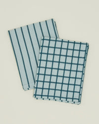 The Essential Dish Towels in Sky/Peacock by Hawkins New York—a set of two with stripe and check patterns—are laid out on a plain light background.