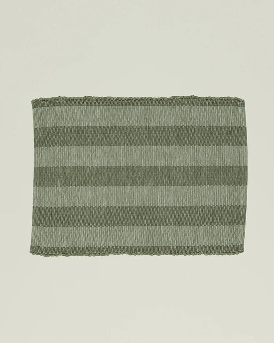 The Essential Floor Mat in Olive by Hawkins New York features recycled fibers with alternating dark and light green horizontal stripes set against a plain light background.