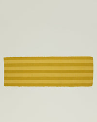The Essential Floor Runner in Mustard by Hawkins New York is a hand-loomed rectangular runner featuring horizontal stripes on a light background, blending artisanal charm with a modern vibe.