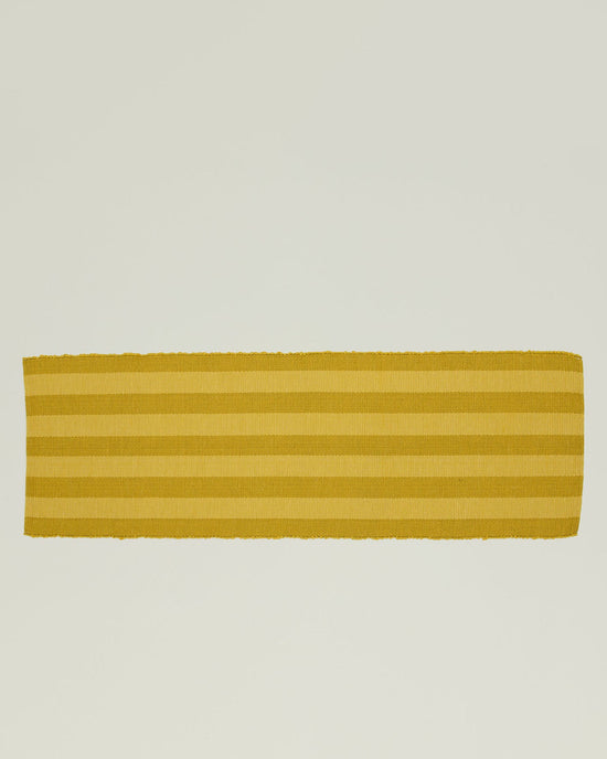 The Essential Floor Runner in Mustard by Hawkins New York is a hand-loomed rectangular runner featuring horizontal stripes on a light background, blending artisanal charm with a modern vibe.