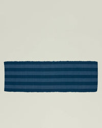 The Essential Floor Runner in Navy by Hawkins New York features dark blue stripes and is crafted from recycled fibers, shown laid flat on a plain, light-colored background.
